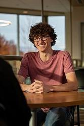 young man smiling sitting at table indoors